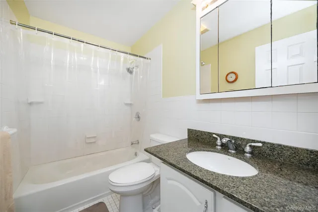 a bathroom with a granite countertop sink mirror vanity and toilet
