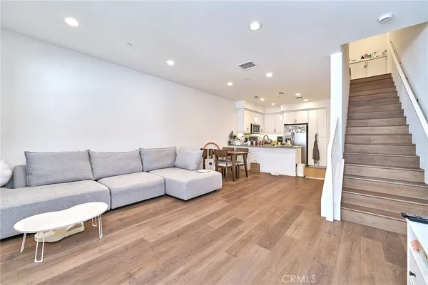 a living room with furniture and kitchen view with wooden floor