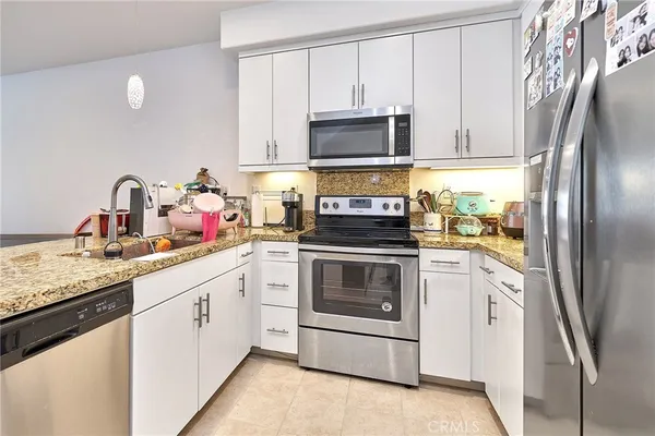 a kitchen with stainless steel appliances granite countertop a refrigerator sink and stove
