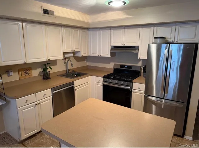 a kitchen with a refrigerator sink and cabinets