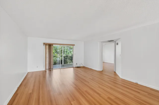 a view of an empty room and window with wooden floor