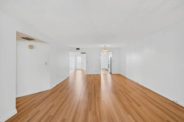 an empty room with wooden floor fan and windows