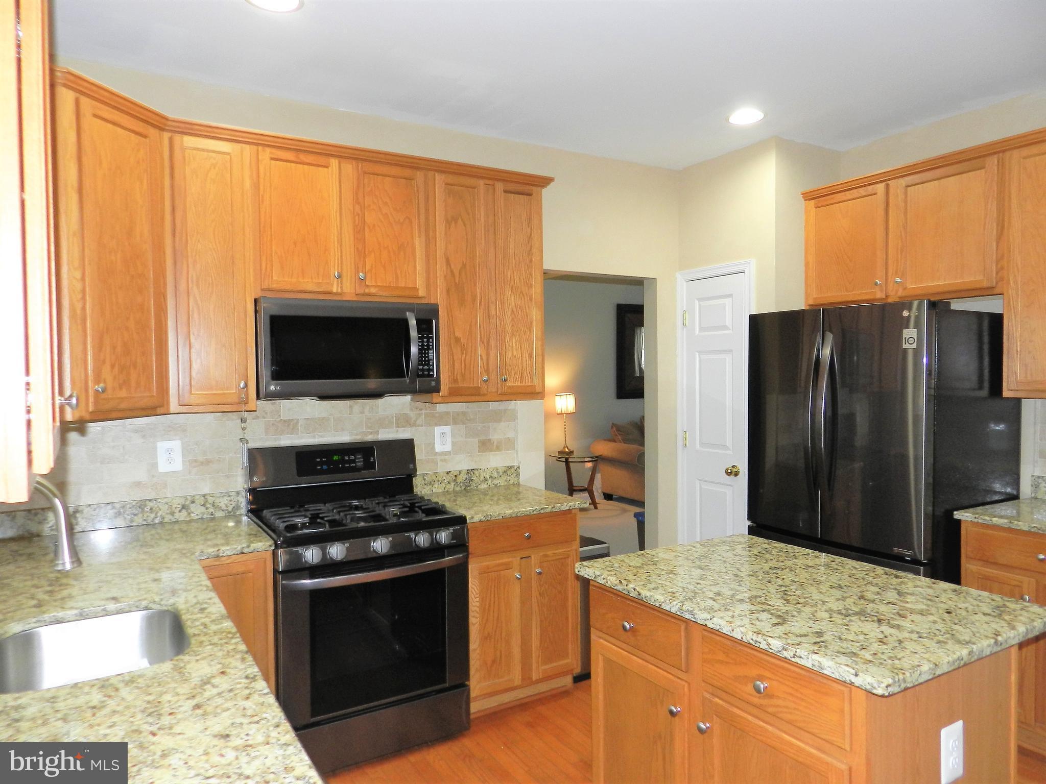 479 Blossom Tree Road Culpeper, VA 22701 - Photo 11 of 30 a kitchen with stainless steel appliances kitchen island granite countertop a stove refrigerator and microwave