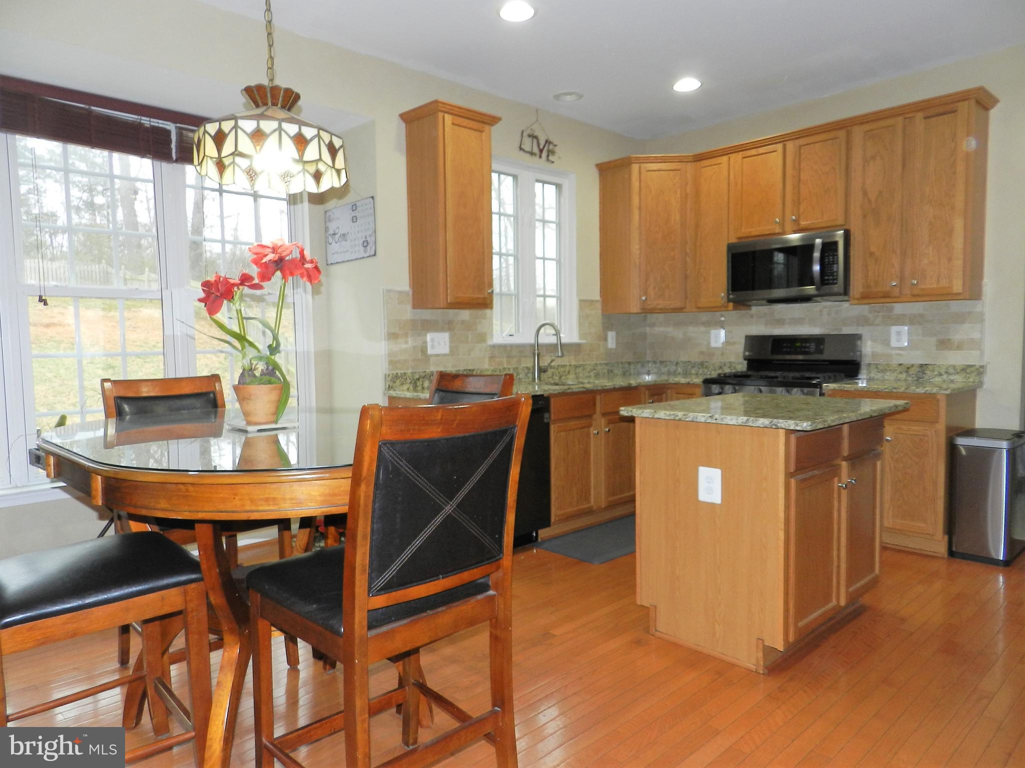 479 Blossom Tree Road Culpeper, VA 22701 - Photo 9 of 30 a kitchen with stainless steel appliances granite countertop wooden cabinets a stove top oven a granite counter top and dining room view