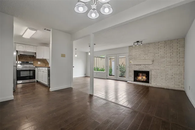 an empty room with wooden floor a fireplace and windows