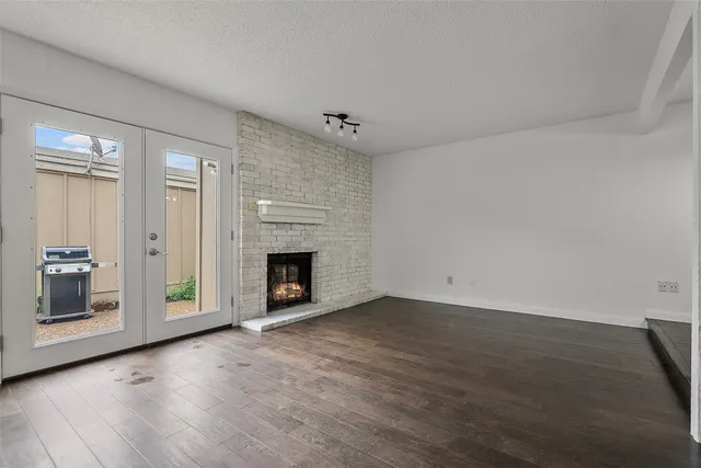 an empty room with wooden floor fireplace and windows