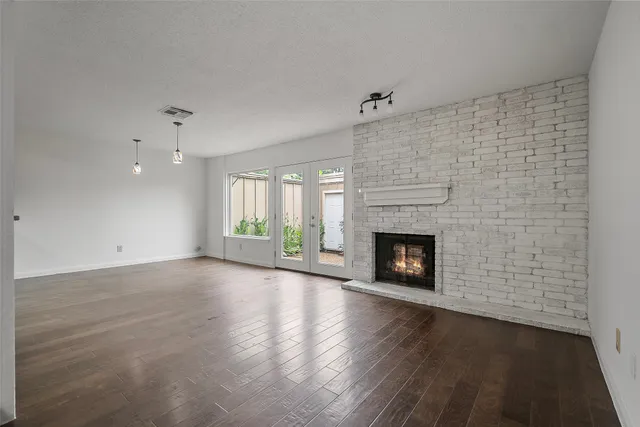 an empty room with wooden floor fireplace and windows