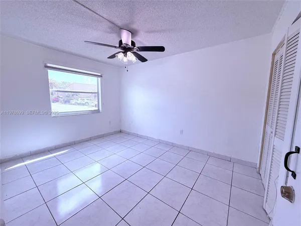 an empty room with windows and fan