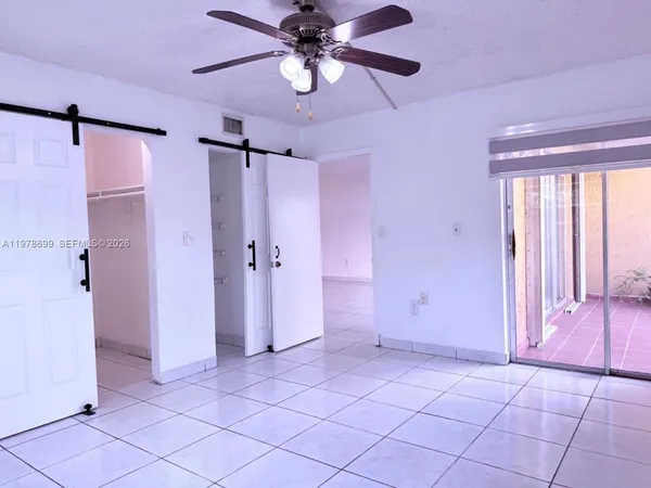 a view of a livingroom with a chandelier fan and windows