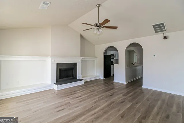 a view of a livingroom with a fireplace a ceiling fan and wooden floor