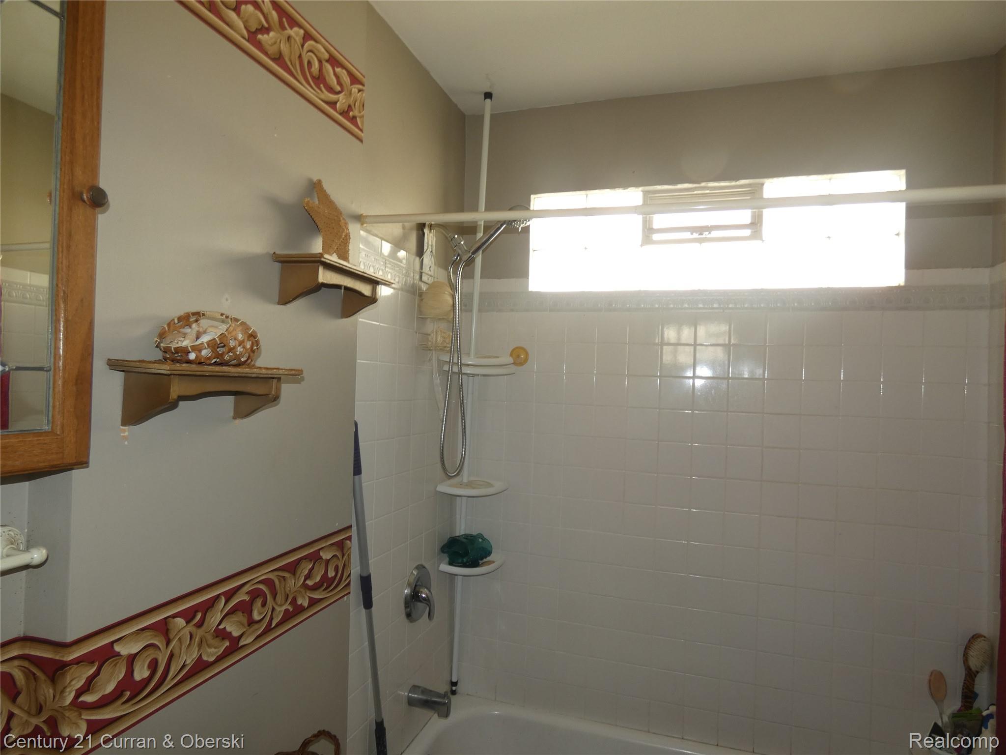 136 East Rundell Street Pontiac, MI 48342 - Photo 10 of 13 Bathroom featuring a white subway tile surround, built-in bathtub, and an overhead window