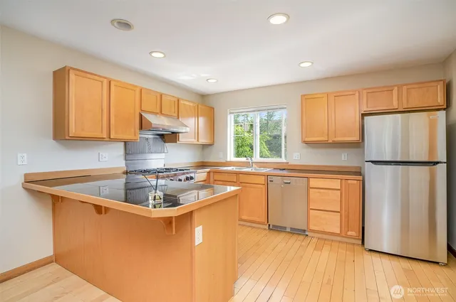 a kitchen with stainless steel appliances granite countertop a sink stove and refrigerator