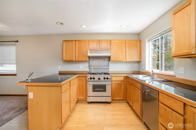 a kitchen with stainless steel appliances granite countertop a sink and a stove