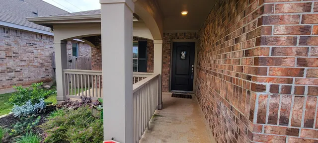 a view of a brick house with a black door and a potted plant