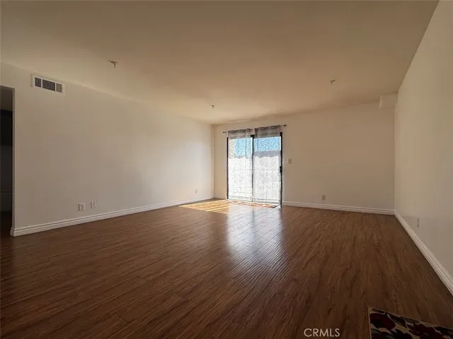 a view of an empty room with wooden floor and windows