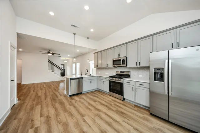 a large kitchen with stainless steel appliances granite countertop a refrigerator a stove a sink dishwasher and a oven with wooden floor