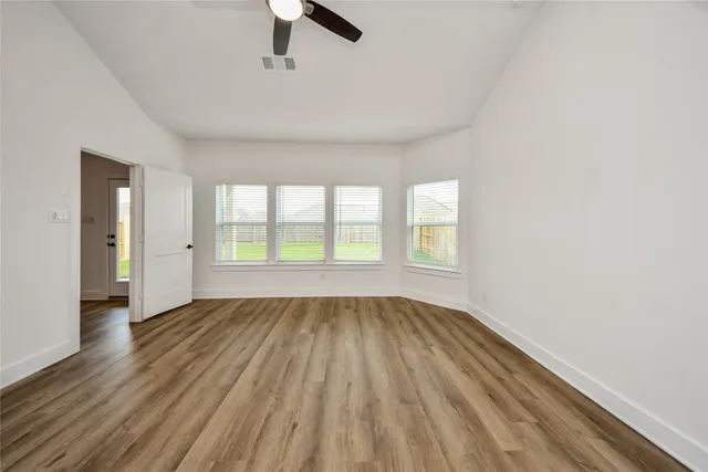 an empty room with wooden floor and windows