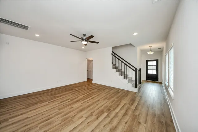 a view of an empty room with wooden floor and a chandelier