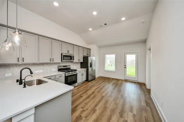 a kitchen with stainless steel appliances granite countertop a sink a stove and a refrigerator