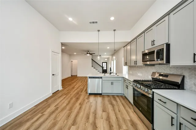 a large kitchen with stainless steel appliances granite countertop a lot of cabinets a stove and a sink