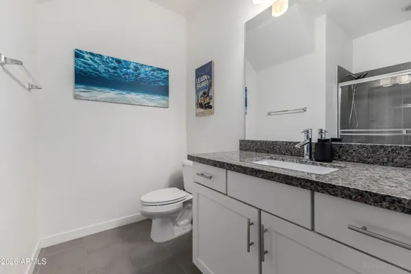 a bathroom with a granite countertop toilet sink and mirror