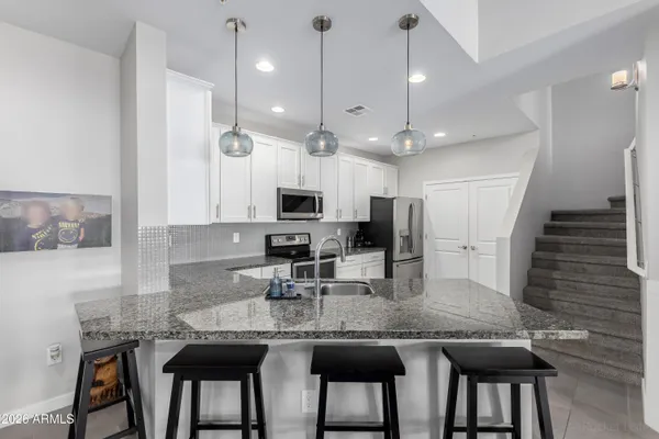 a kitchen with kitchen island granite countertop a table chairs refrigerator and microwave