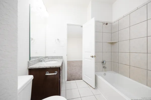 a bathroom with a granite countertop sink a toilet and bathtub