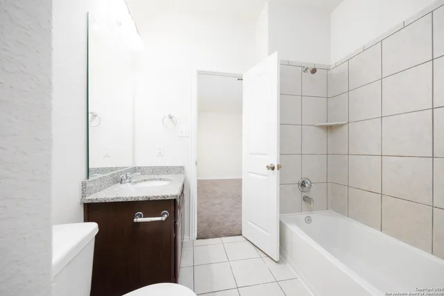 a bathroom with a granite countertop sink a toilet and bathtub
