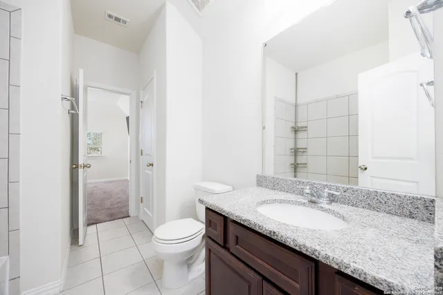 a bathroom with a granite countertop sink a toilet and shower