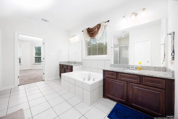 a spacious bathroom with a granite countertop sink mirror and bathtub