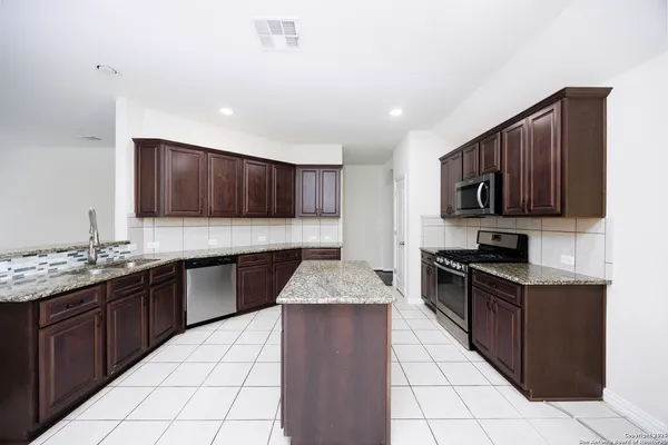 a kitchen with stainless steel appliances granite countertop wooden cabinets a stove top oven a sink and dishwasher