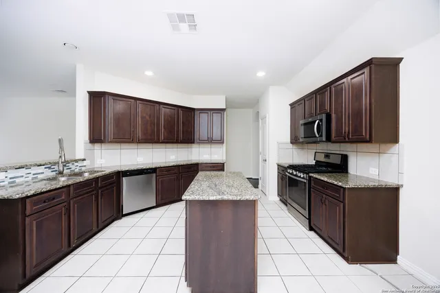 a kitchen with stainless steel appliances granite countertop wooden cabinets a stove top oven a sink and dishwasher