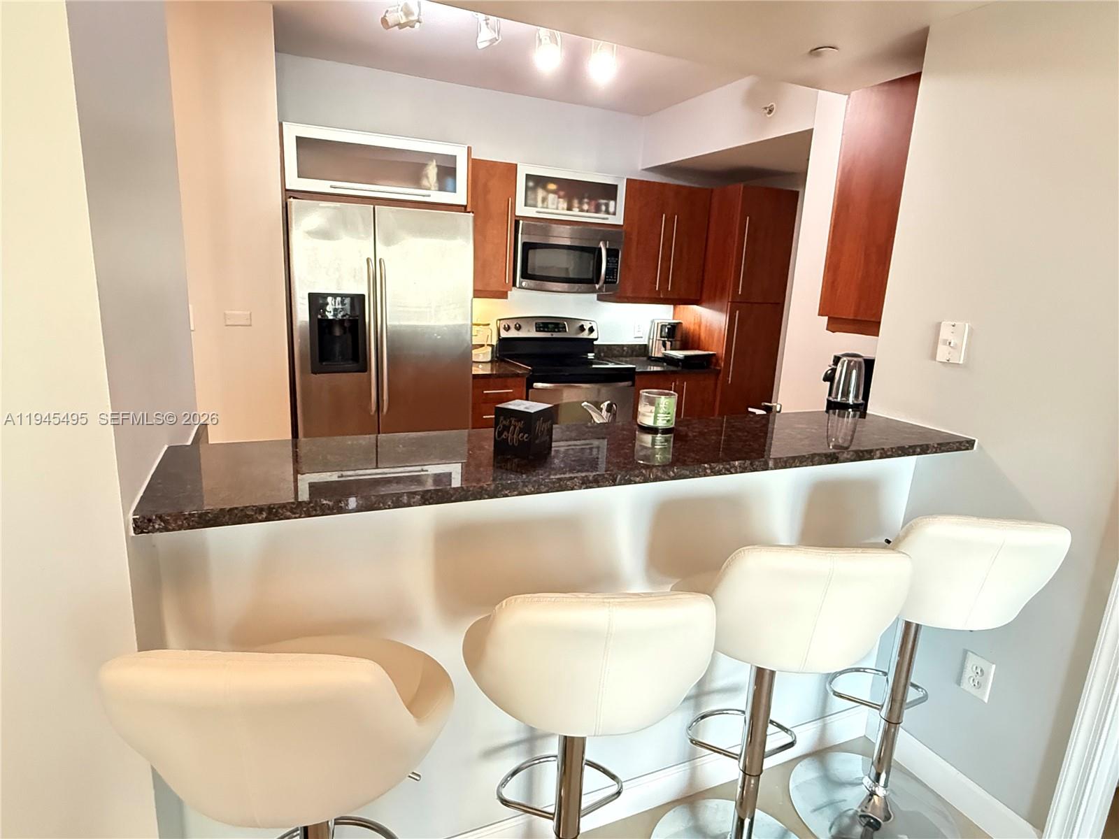 7350 Southwest 89th Street, Unit 1908S Miami, FL 33156 - Photo 11 of 28 a kitchen with stainless steel appliances kitchen island granite countertop a refrigerator and a stove