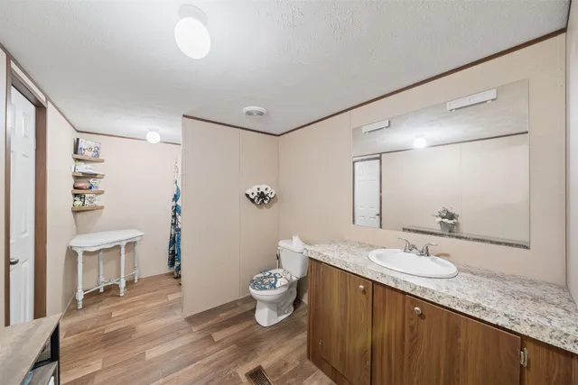 a spacious bathroom with a granite countertop sink a toilet a mirror and shower