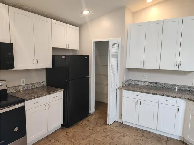 a kitchen with granite countertop white cabinets and refrigerator