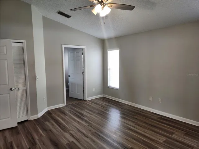 an empty room with wooden floor and windows