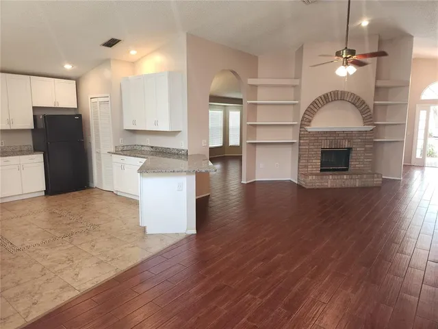 a open kitchen with a refrigerator and wooden floor