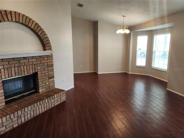 an empty room with wooden floor fireplace and windows
