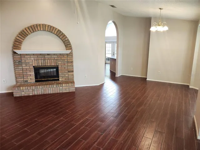an empty room with wooden floor fireplace and windows