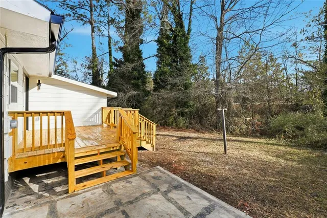 a view of a backyard with large trees and wooden fence