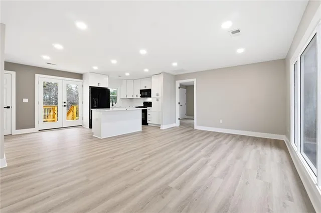 a view of a kitchen with an empty room and wooden floor
