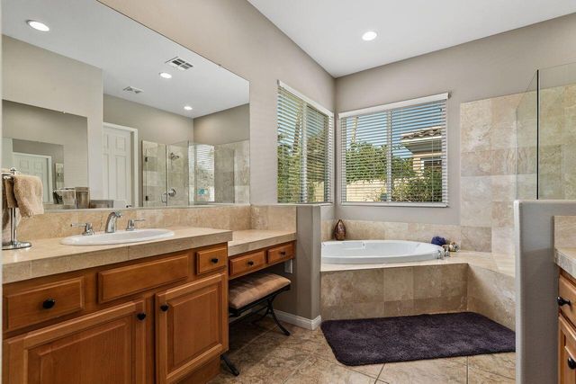 a bathroom with a tub a sink and a large mirror