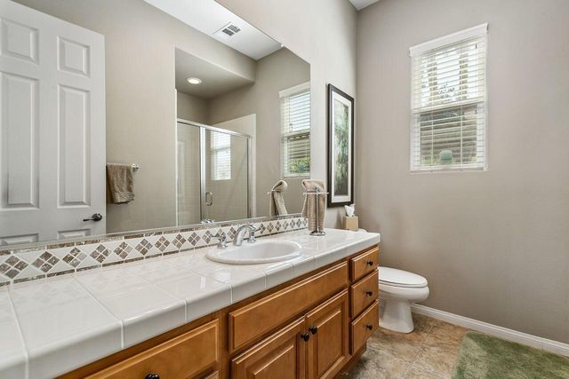a bathroom with a granite countertop sink a toilet and a mirror