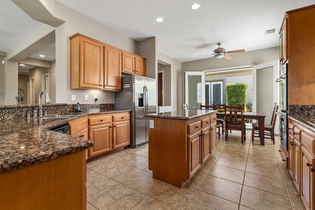 a kitchen with stainless steel appliances granite countertop wooden cabinets a sink a stove a dining table and chairs