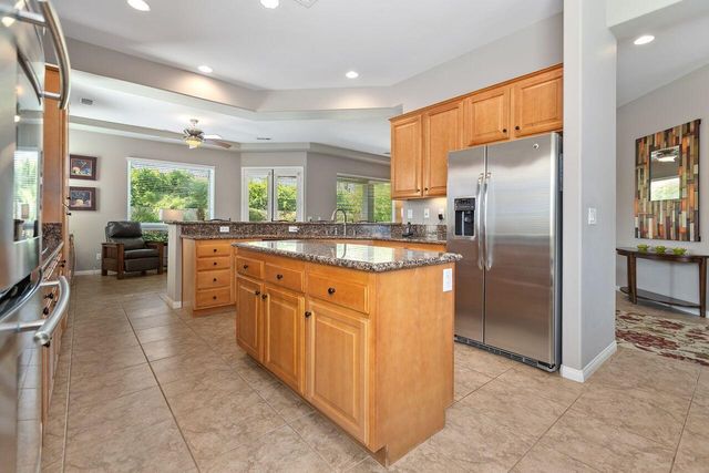 a kitchen with stainless steel appliances granite countertop a refrigerator a sink a stove top oven and cabinets