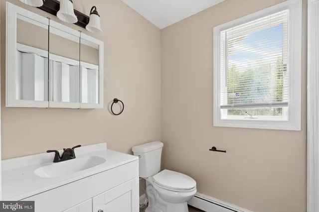 a bathroom with a toilet sink vanity and mirror