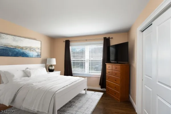 a bedroom with a large bed and a flat tv screen on dresser