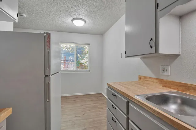 a view of a kitchen that shows a sink and wooden floor