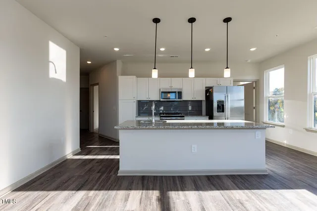 a kitchen with stainless steel appliances granite countertop a sink a stove and a wooden floors