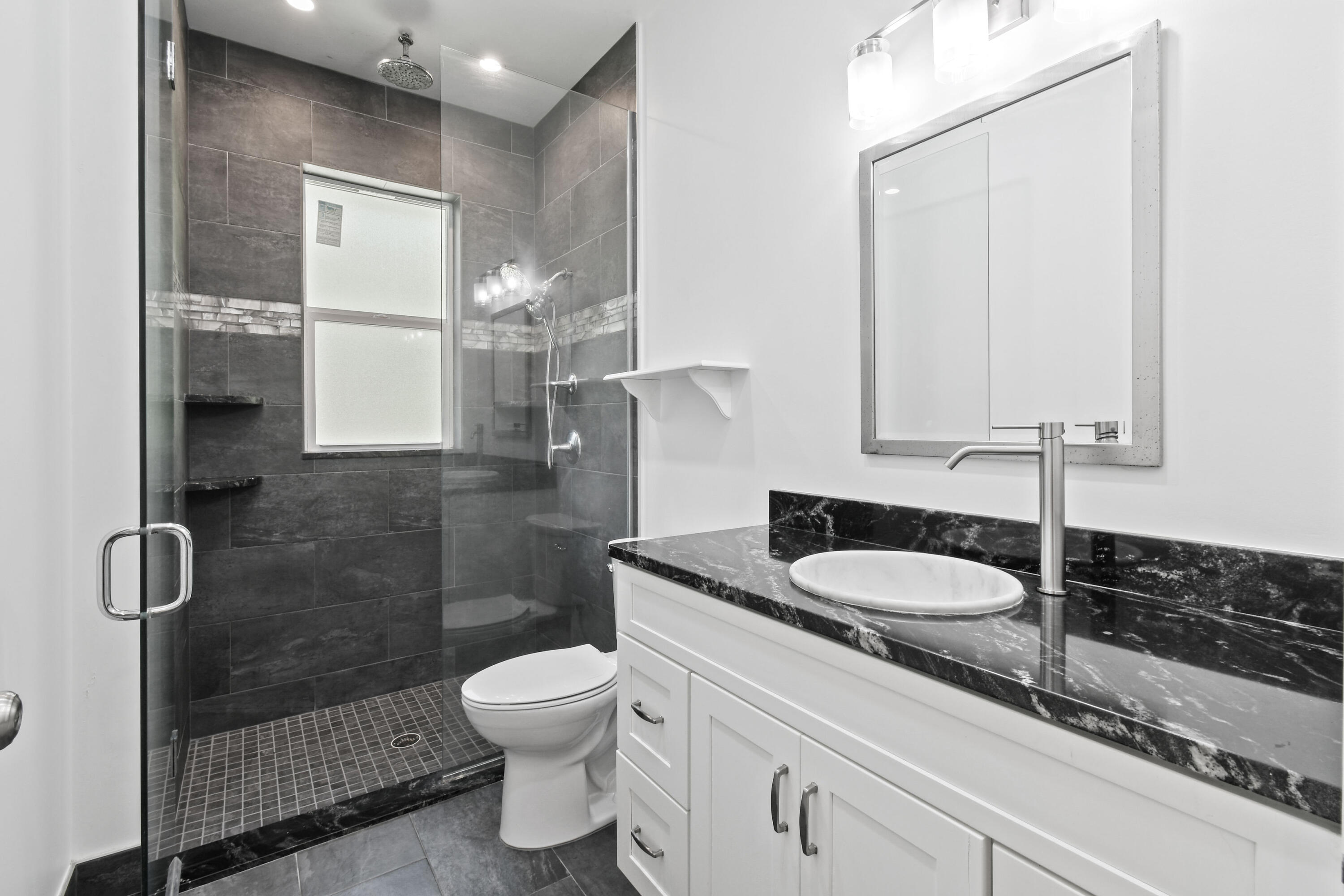 5782 Russakis Road Fort Pierce, FL 34951 - Photo 31 of 90 a bathroom with a granite countertop sink a toilet a mirror and shower